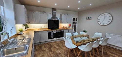 a kitchen with a table and chairs and a clock on the wall at Antfield house in Inverness