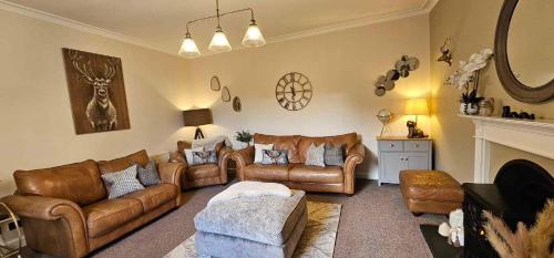 a living room with leather couches and a fireplace at Antfield house in Inverness