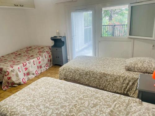 une chambre avec deux lits et une fenêtre dans l'établissement Maison 2 P- Peymeinade lotissement avec Piscine, à Peymeinade