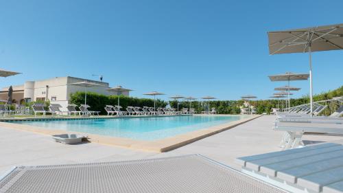 a large swimming pool with chairs and umbrellas at Delle Rose Horses Club in Torre Vado