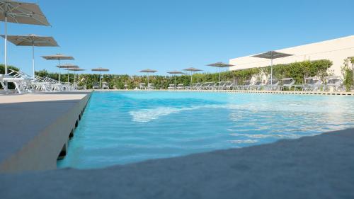 a swimming pool with chairs and umbrellas at a resort at Delle Rose Horses Club in Torre Vado