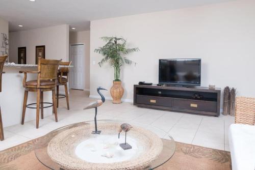 a living room with a tv and two birds on a table at Spacious Beach-Inspired Condo with Resort-Style Amenities & Beach Club Access in Coco