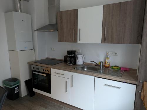 a small kitchen with white cabinets and a sink at Charmantes EG-Apartment nahe Südstrand und City in Wilhelmshaven