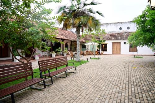 un patio con bancos y árboles y un edificio en El monarca, en Mompox