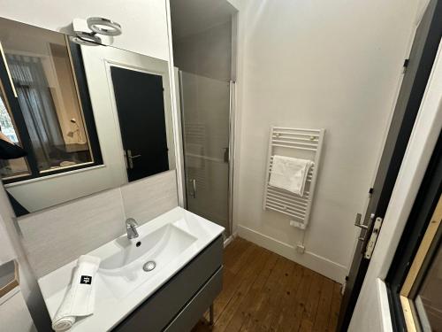 une salle de bain blanche avec un lavabo et un miroir dans l'établissement LE Cosy de Grammont T2, à Tours