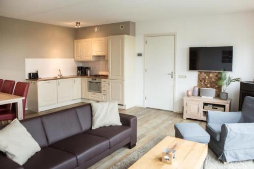 a living room with a couch and a kitchen at Weidevilla XXL in Hollum