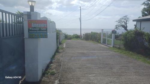 an empty street with a sign on a fence at Gîtes Capra Pomme Surette piscine et spa in Bouillante