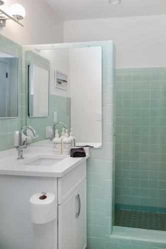 a bathroom with a sink and a shower with green tiles at Haley's Court Boutique Motel in Saint Augustine