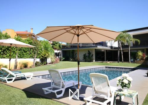a couple of chairs and an umbrella next to a pool at MyStay - Casa 134 in Ribeirão