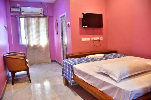 a bedroom with a bed and a tv on the wall at City Plaza Lodge in kāraikāl