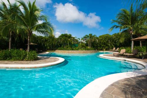 a swimming pool with blue water and palm trees at 1-Bedroom Near Pool in Coco