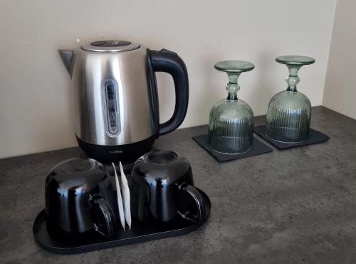 - une cafetière sur un plateau avec deux vases en verre dans l'établissement Antica Dimora San Crisante - centro storico, à LʼAquila