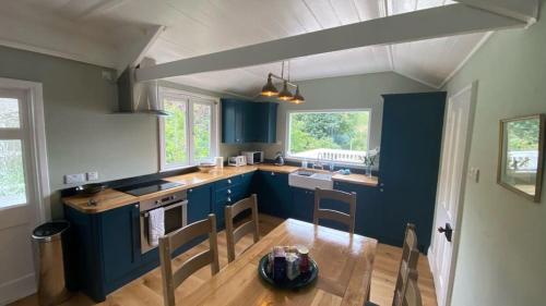 a kitchen with blue cabinets and a table and chairs at Lower Hill Cottage w/Swedish Hot Tub in Bodmin