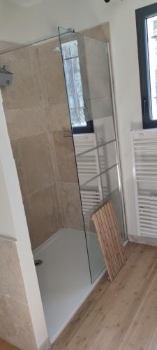 - une douche en verre dans une chambre avec une chaise en bois dans l'établissement Le Mas du 1934, à Lorgues