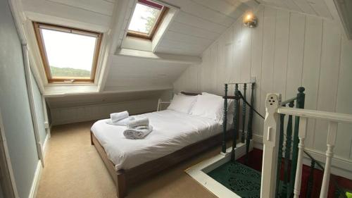 a bedroom with a bed with white sheets and a window at Lower Hill Cottage w/Swedish Hot Tub in Bodmin