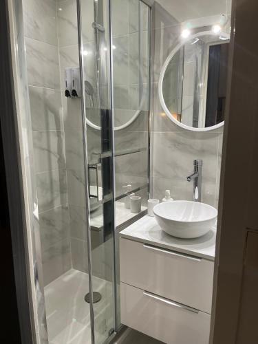 une salle de bain blanche avec un lavabo et une douche dans l'établissement Cosy Angevin - Joli petit appartement, à Angers