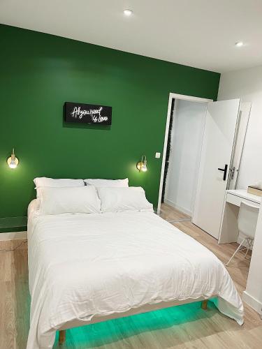 - une chambre avec un mur vert et un lit blanc dans l'établissement Cosy Angevin - Joli petit appartement, à Angers