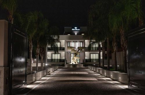 a hallway with palm trees in front of a building at night at Hotel Manuela in Varcaturo