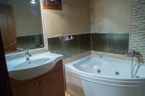 a bathroom with a tub and a sink at Ξενώνας Σκαλοπάτια in Palaios Agios Athanasios