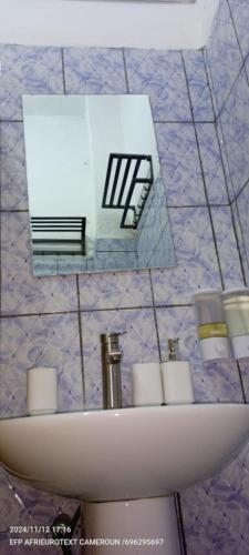 a white sink in a bathroom with a mirror at AFRIEUROTEXT Kamerun-High Standing-Appartements-Wifi-Security-Restaurant-modern Kitchen in Yaoundé
