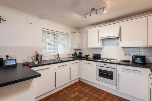 a kitchen with white cabinets and black counter tops at Carbis Bay and Spa Hotel in St Ives