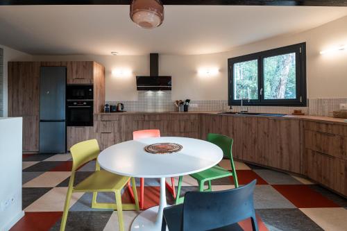 une cuisine avec une table blanche et des chaises colorées dans l'établissement Villa COUDINEY, à Biscarrosse
