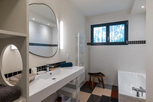 une salle de bain avec un lavabo, une baignoire et un miroir dans l'établissement Villa COUDINEY, à Biscarrosse