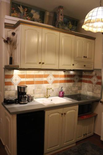 a kitchen with white cabinets and a sink at Βoka's House in Arachova