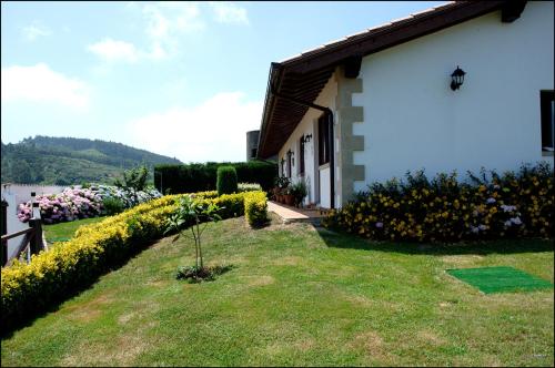 una casa con un jardín con flores delante en Vivienda Rural Las Candelas, en Oreña