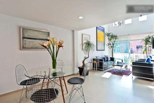 a living room with a glass table and chairs at Duplex Penthouse Zona Rosa in Mexico City