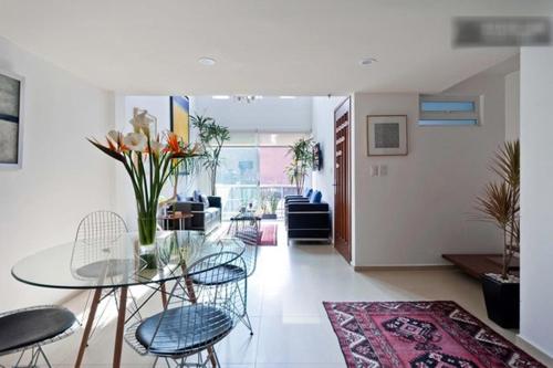 a living room with a glass table and chairs at Duplex Penthouse Zona Rosa in Mexico City