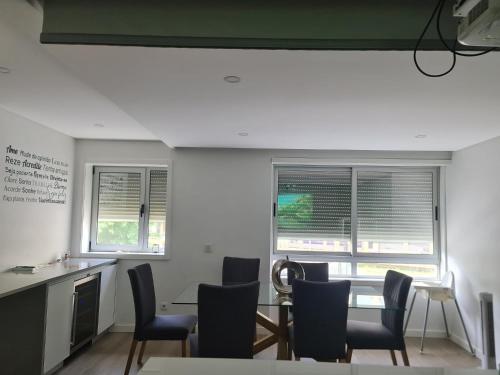 a kitchen with a table and chairs and two windows at Feira Central Loft in Santa Maria da Feira