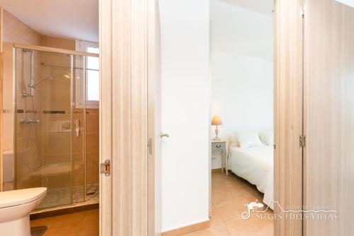 a bathroom with a shower and a toilet and a bed at Villa Senia, close to Sitges with private pool in Olivella