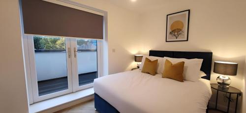 a bedroom with a bed and two large windows at Hybrid Resi - London, Mitcham close to Tooting and Wimbledon in Mitcham