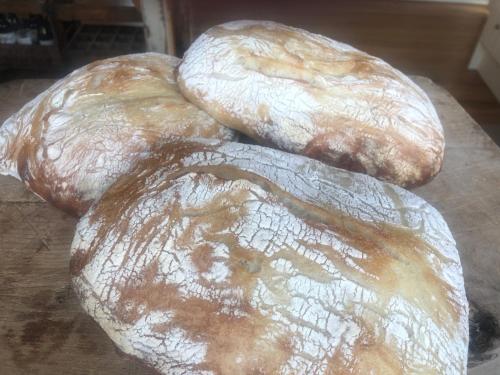 three loaves of bread sitting on top of a table at The Wash-House historic Cottage Close to Hobbiton in Matamata