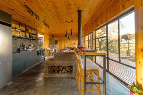 a kitchen with a bar and a fireplace in a house at Cabana na Serra Lareira e Vista Deslumbrante in Rio Rufino