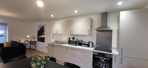 a kitchen with white cabinets and a stove top oven at Hybrid Resi - London, Mitcham close to Tooting and Wimbledon in Mitcham