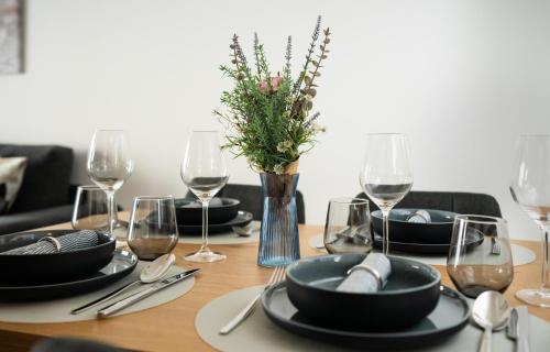 a wooden table with black plates and wine glasses at REITZ - Apartment I Zentrale Lage I Stellplatz I 55qm I 2 Zimmer I Küche I Bad I Terrasse in Bad Hersfeld