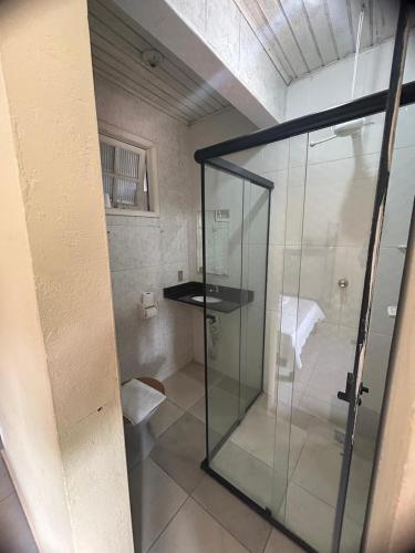 a glass shower stall in a room with a bed at Pousada Flor de Jambo in Ubatuba
