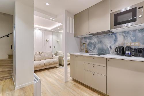 une cuisine avec des armoires blanches et un salon dans l'établissement Coeur du Marais Arts&Metiers Magnifique Appartement, à Paris