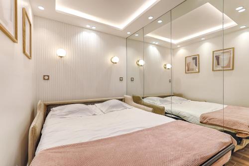 - 2 lits dans une chambre avec des miroirs sur le mur dans l'établissement Coeur du Marais Arts&Metiers Magnifique Appartement, à Paris