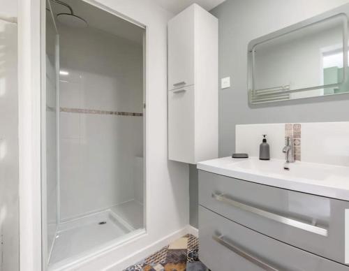 une salle de bain blanche avec un lavabo et une douche dans l'établissement Maison 5 chambres idéal famille et groupe, à Anzin