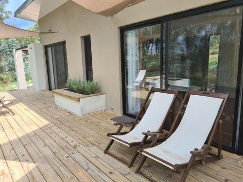 two chairs sitting on a deck with a house at Cerro Místico Hotel de Campo in Minas