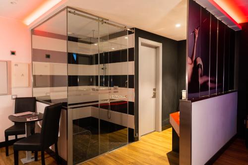 a bathroom with a glass shower with a table and chairs at Motel Avenue in Valongo