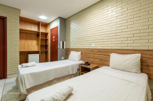 a room with two beds and a brick wall at Rede Andrade Goiania Centro in Goiânia