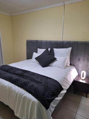a large bed with black and white sheets and pillows at The Cozy Nook in Piet Retief