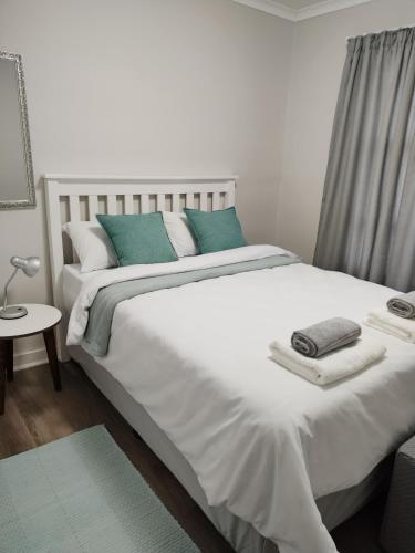 a bedroom with a large white bed with blue pillows at 1 On Wilderness in Klein Brak Rivier