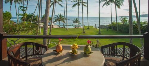 a table with three vases on it with a view of the ocean at Oceanfront Citakara Sari Villas in Candidasa