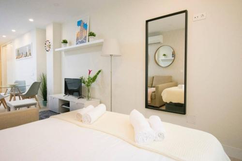 sypialnia z białym łóżkiem i lustrem w obiekcie NEW AND COZY-STUDIO-CHUECA w Madrycie