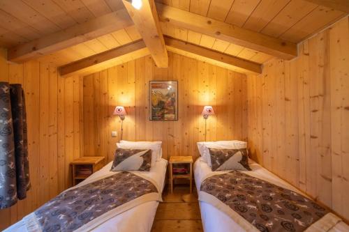 two beds in a room with wooden walls at Les Chalets du Bonheur in Les Houches